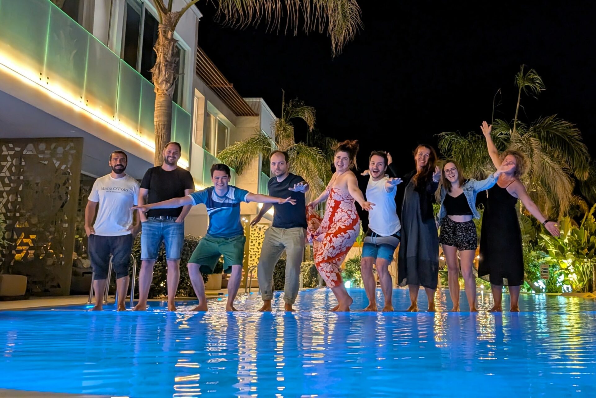 Eine Gruppe von Menschen am Poolrand bei Nacht