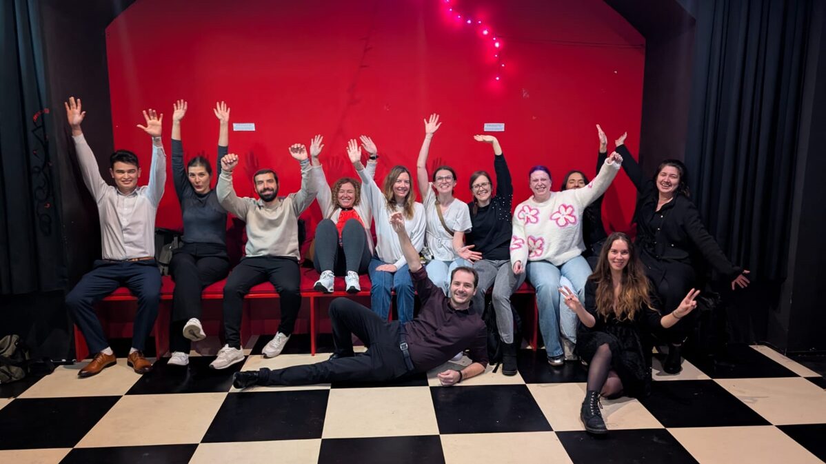 Eine Gruppe von Menschen in einem Raum mit einer roten Wand und einem Schachbrettboden